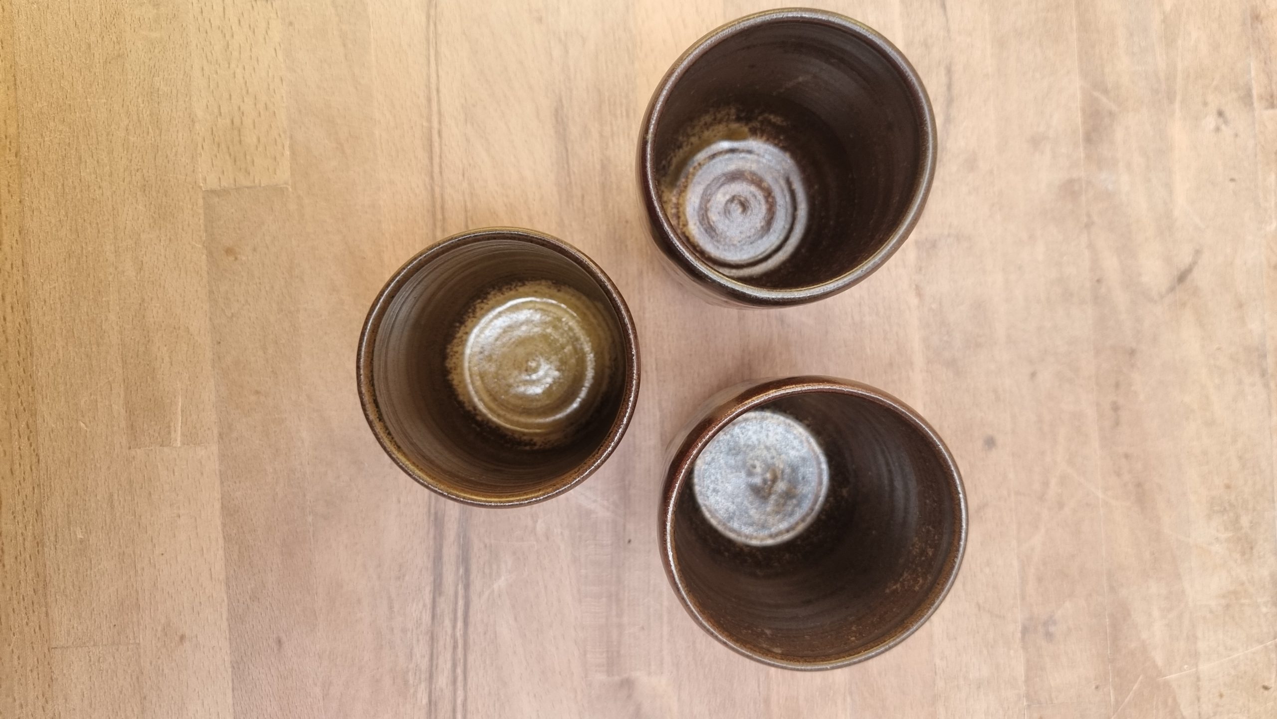 view into 3 brown beakers from above. wooden background
