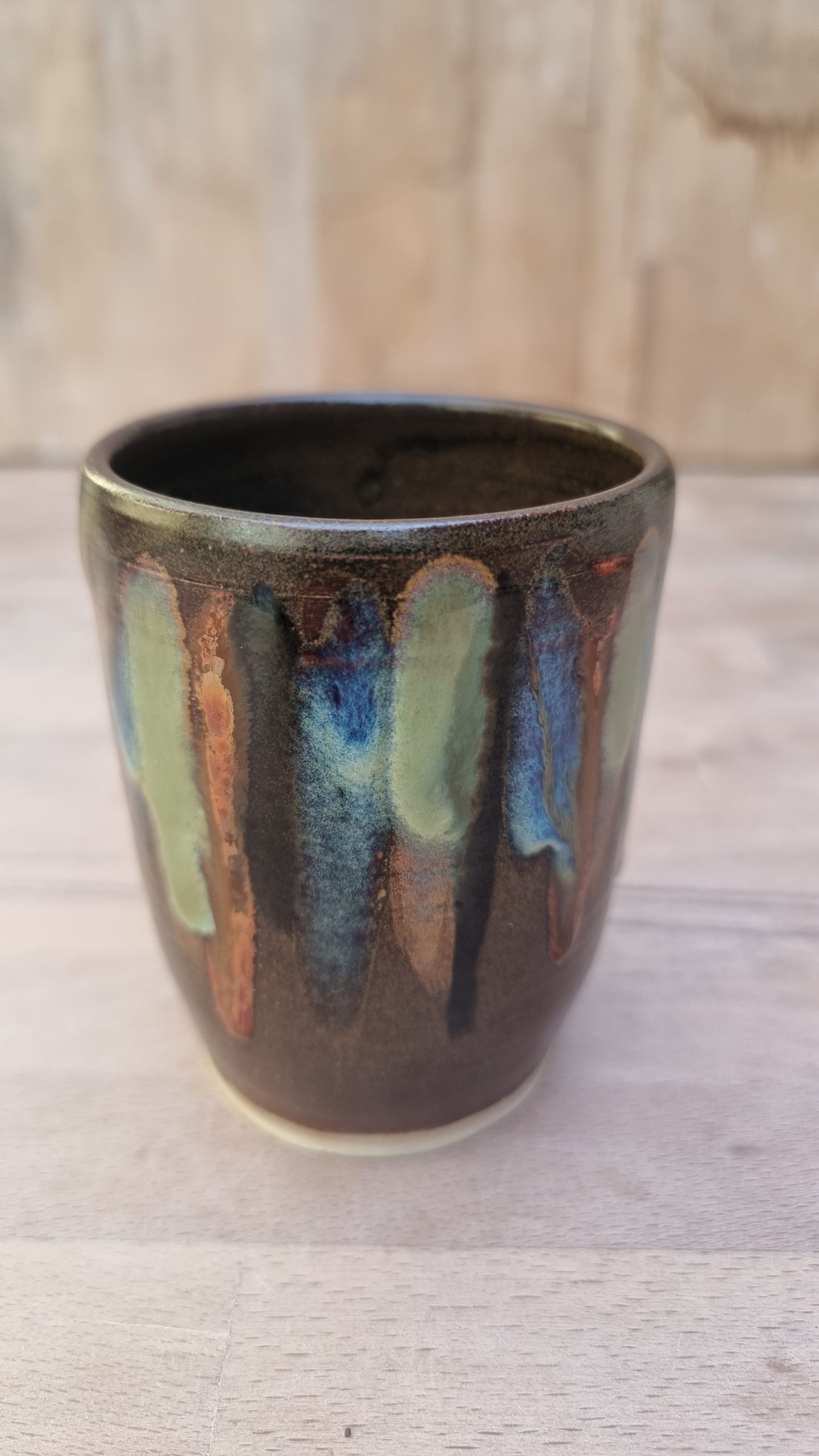 brown and coloured beaker. wooden bench and backing.