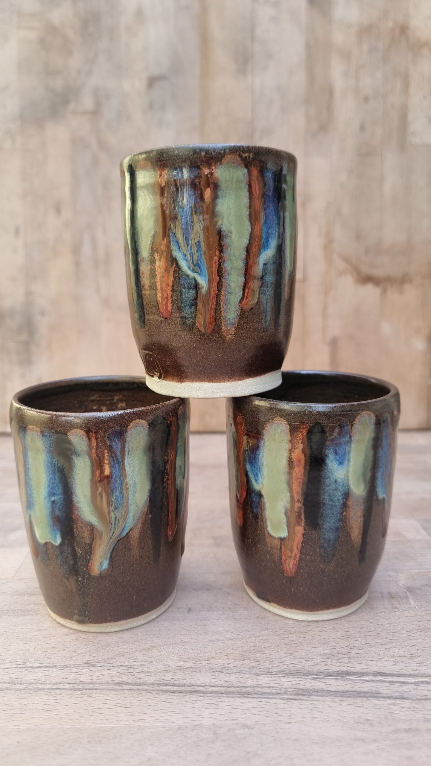 brown and coloured beaker. wooden bench and backing.