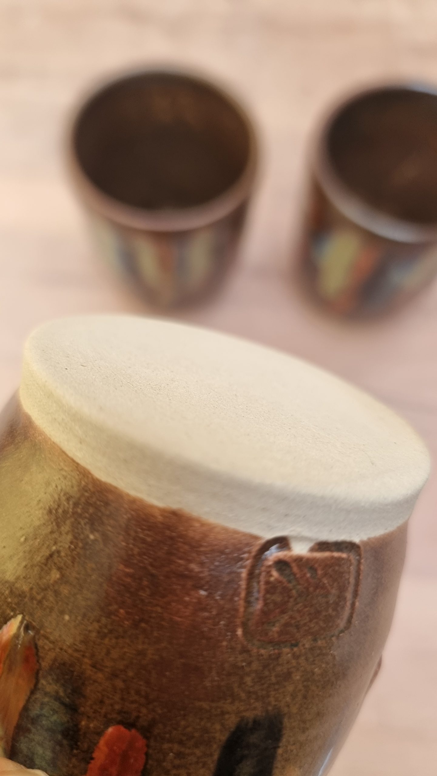 white clay base of brown and coloured beaker. wooden bench and backing.