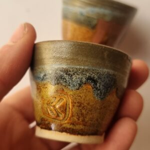 blue and yellow shot glass held in hand